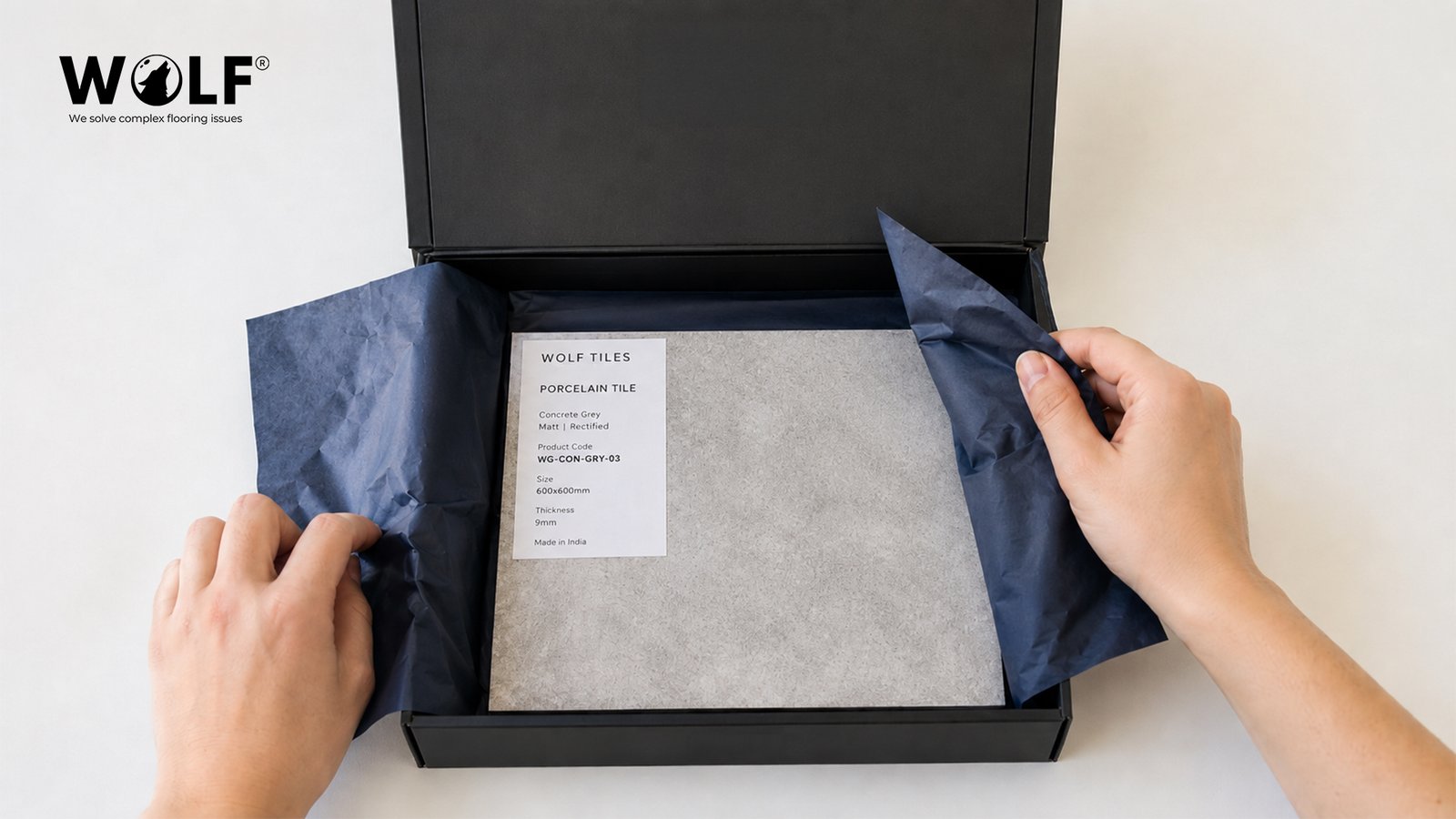 Wolf porcelain tile sample box opened to reveal labeled Concrete Grey tile with product code and specifications